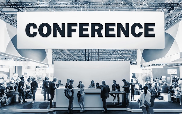 Crowd of people at a trade show booth with a banner and the\
text conference