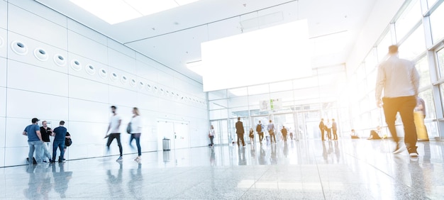 Crowd of people walking at a trade show floor with banner\
including copy space. ideal for websites and magazines layouts