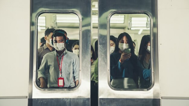 混雑した公共の地下鉄の電車の旅でフェイスマスクを着用している人々の群衆