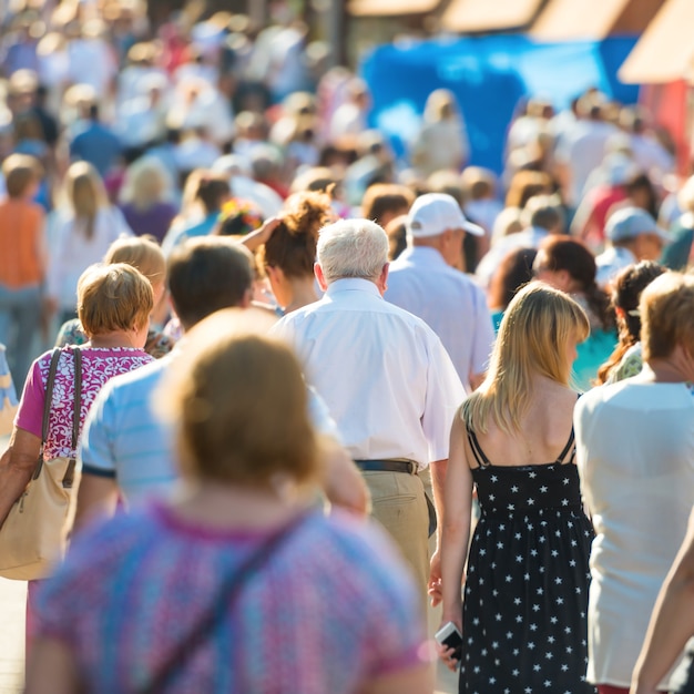 Crowd of people with old man in center walking on the busy city street