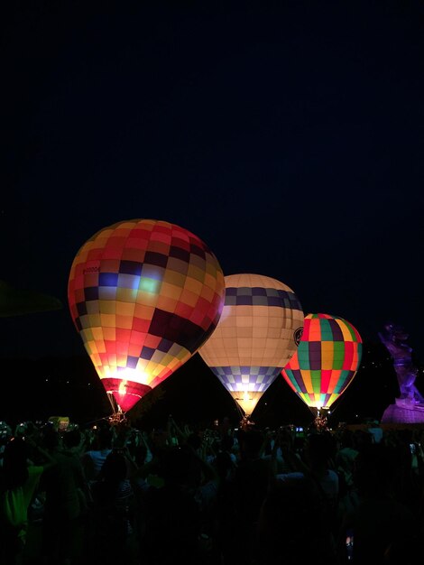 Foto folla con mongolfiera illuminata contro il cielo limpido di notte