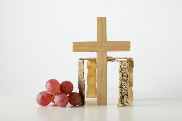Foto corona d'uva e croce di legno su sfondo bianco