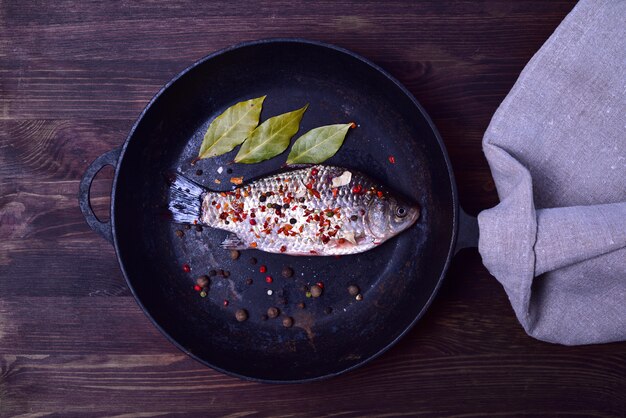 Crucian carp in spices on a black cast-iron frying pan