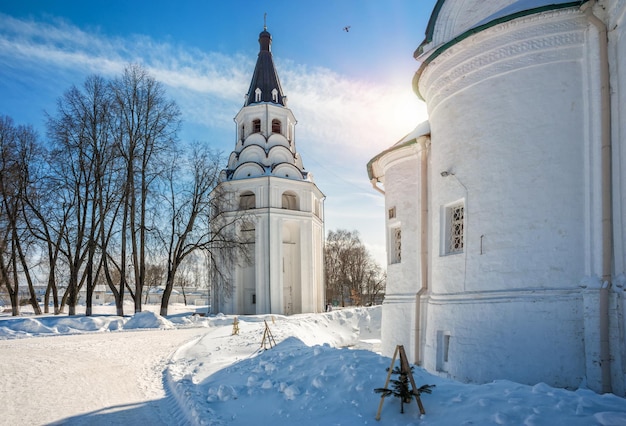 Crucifix churchbell tower in Alexandrov Sloboda against the background of blue sky and white snow