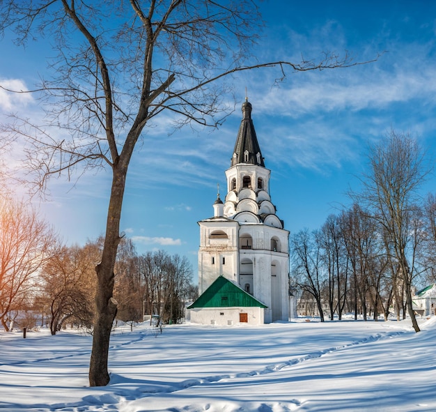 Crucifix churchbell tower under a tree in Alexandrovskaya Sloboda on a sunny winter day