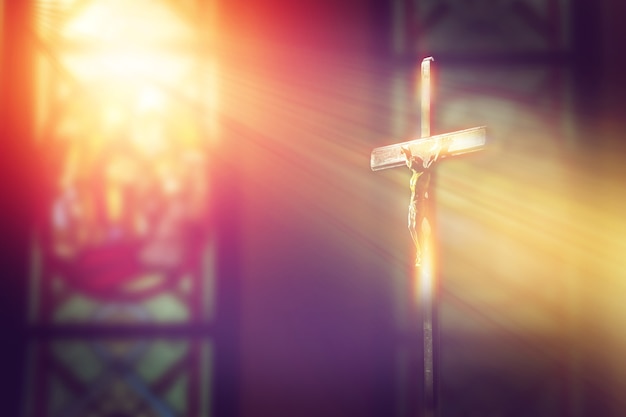 Photo crucifix, jesus on the cross in church with ray of light from stained glass