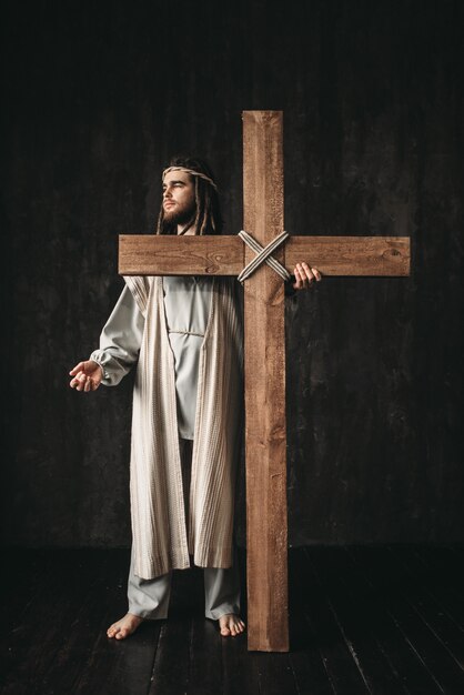 Crucifixion of Jesus Christ, symbol of christian religion. Man with cross on black