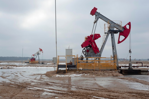 Foto presa della pompa del petrolio greggio al giacimento di petrolio sullo sfondo del tramonto produzione di greggio fossile e combustibili produzione di petrolio piattaforma di perforazione petrolifera e torre di perforazione prezzi del petrolio greggio globale energia domanda di petrolio