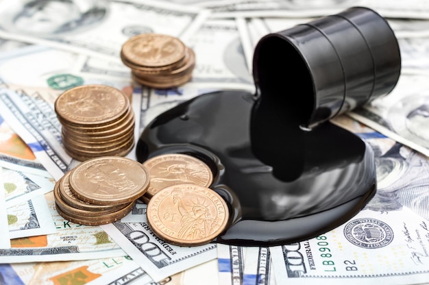 Crude oil spilled from barrel and golden coins on the background of dollars Business concept