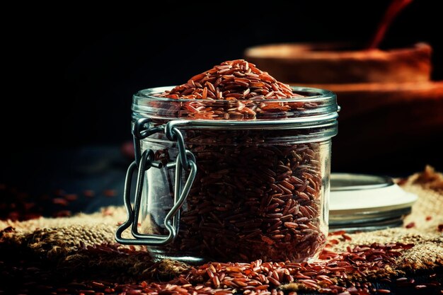 Crude red rice in a glass jar black background selective focus