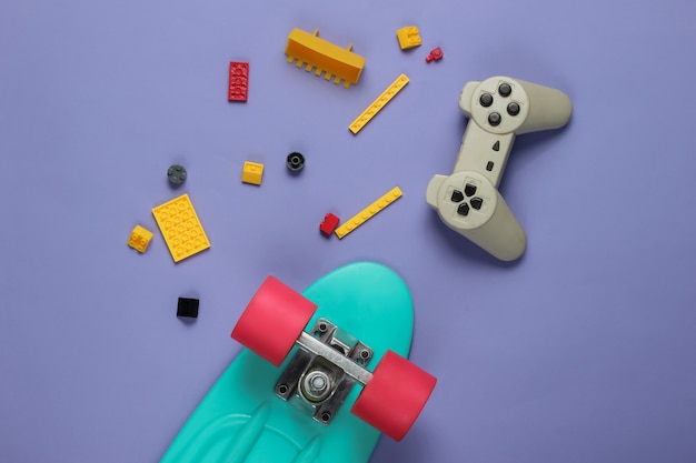 Cruiser board, gamepad, toy bricks on purple