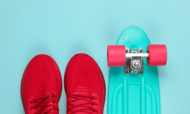 Cruiser board and red sneakers on blue background.