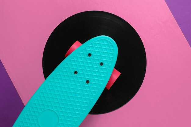 Cruiserboard op vinylplaat. Paars roze achtergrond. Jeugd retro stijl concept. jaren 80. Bovenaanzicht