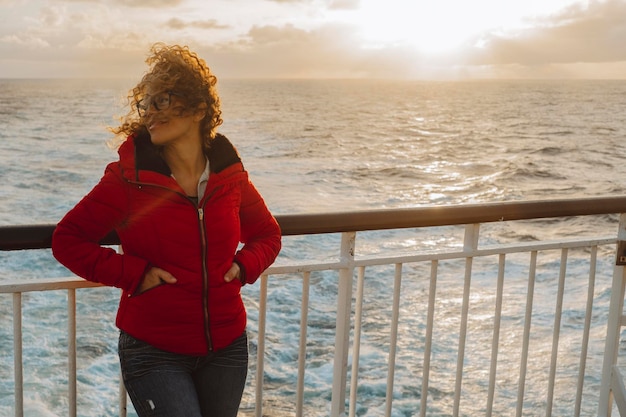 Cruiseschip vakantie vrouw genieten van zonsondergang op reizen op zee Reiziger gelukkige vrouw in rode jas kijken naar oceaan ontspannen op luxe cruiseschip boot Mensen en veerboot vervoer Reisactiviteit