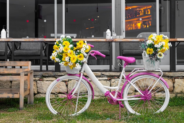 Cruising pink bike with bouquets of flowers on the background of a cafe