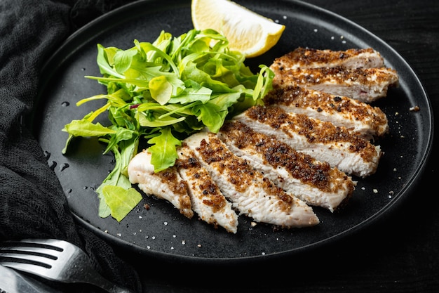 Filetto di petto di pollo sbriciolato alla griglia, sul tavolo di legno nero black