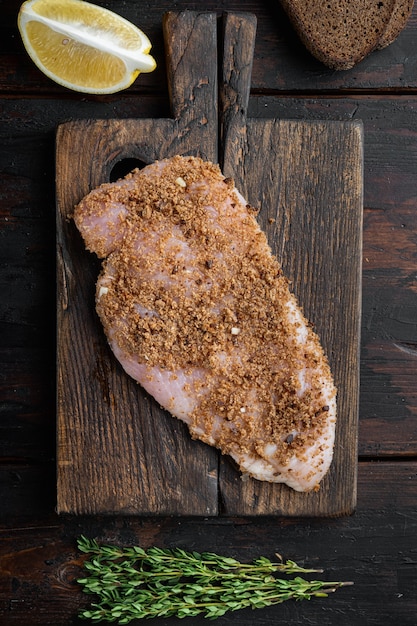 Photo crumbed uncooked chicken breasts ingredient, on wooden table