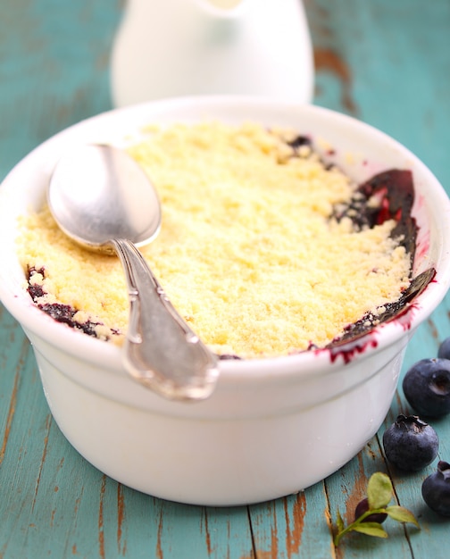 Crumble with blueberry, bilberry in white plate