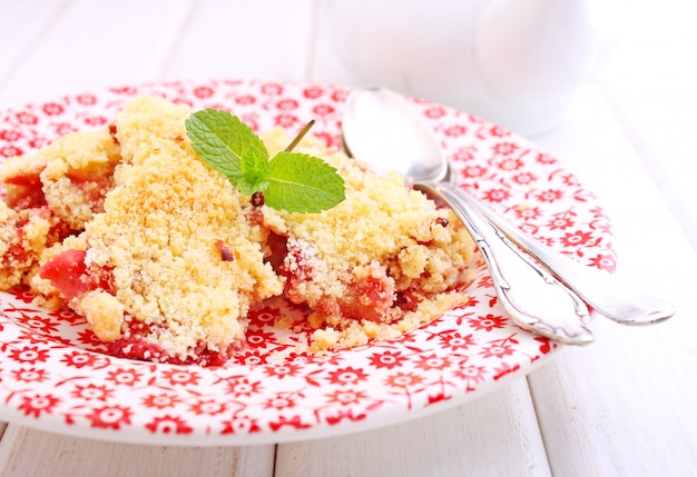 Crumble with strawberries in white plate on a blue background