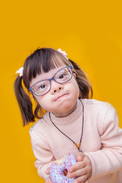 Si sbriciola dappertutto. piccolo bambino interessato con gli occhiali trasparenti e la bocca piena di gustosa ciambella