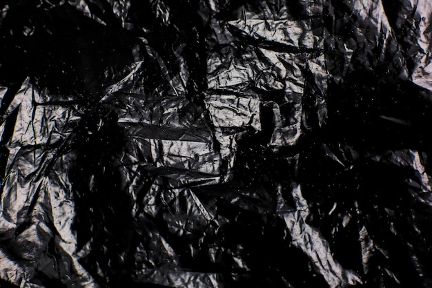 Photo crumpled black plastic bag texture background glossy polyethylene overlay