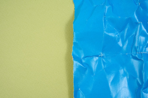 Crumpled blue cardboard sheet of paper on green background, copy space