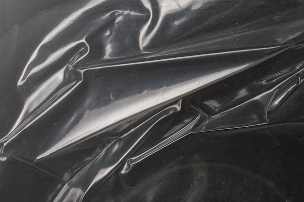 Crumpled glossy dark polyethylene texture