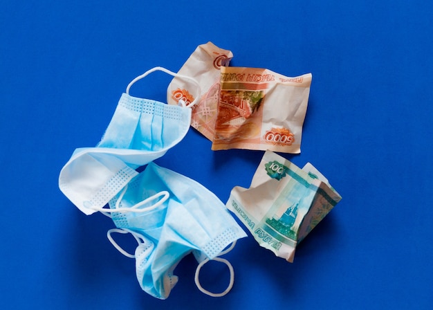 Crumpled medical mask against coronovirus and crumpled Russian money on a blue background.