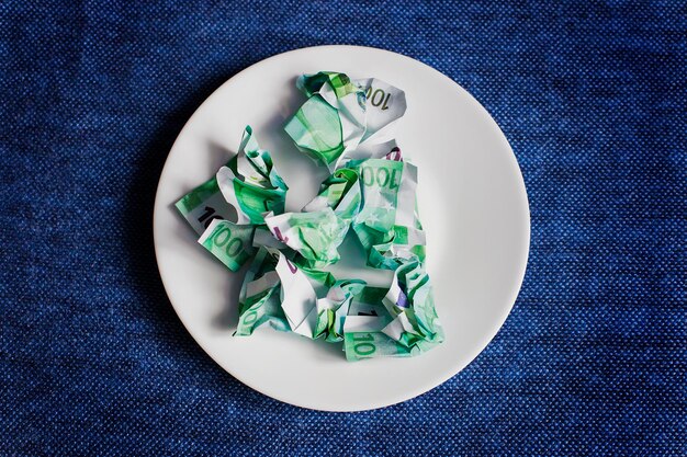 Crumpled money on a plate blue background