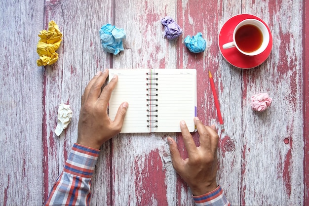 Crumpled paper ball and notepad on wooden table.