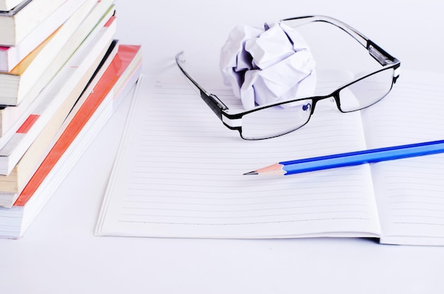 Photo crumpled paper ball with eyeglasses and pencil on open book