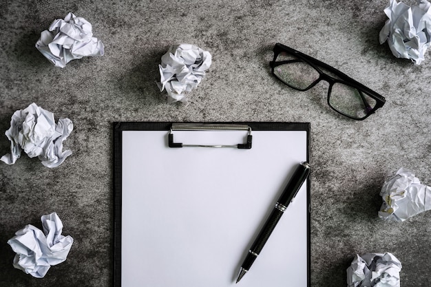 Crumpled paper balls with eye glasses and file folder on desk office, creativity problems concept