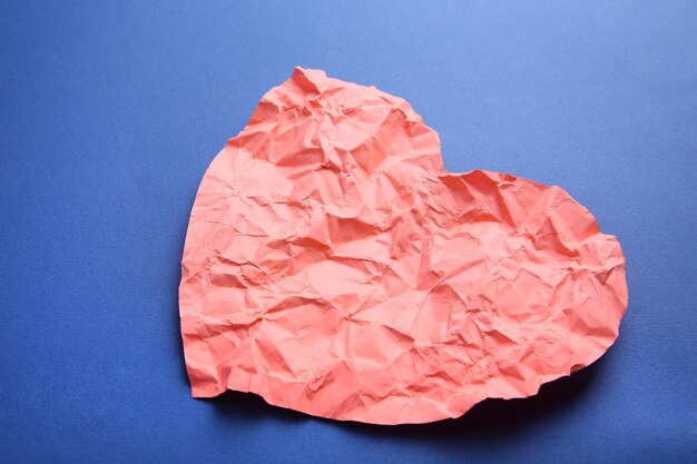 Crumpled paper heart on blue background