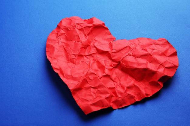 Crumpled paper heart on blue background