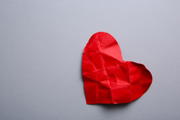 Crumpled paper heart on gray background