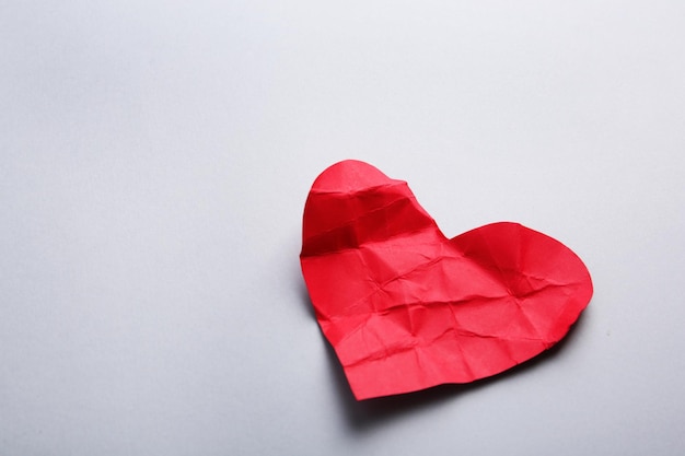 Crumpled paper heart on gray background