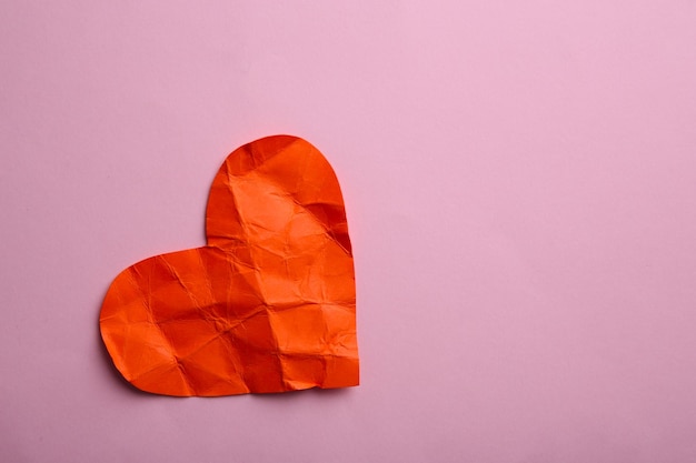 Crumpled paper heart on pink background