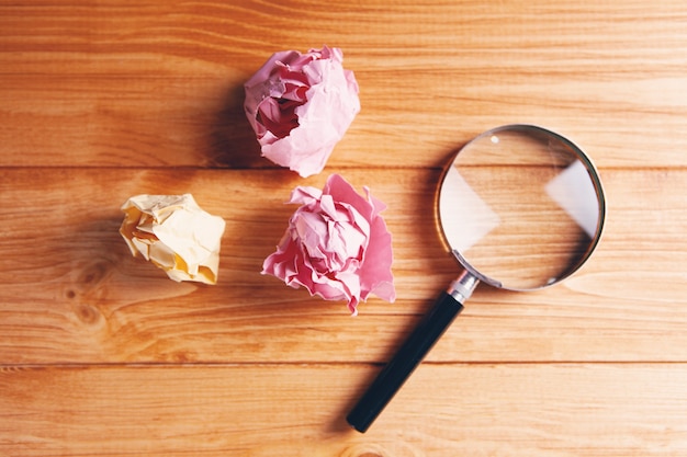 Crumpled papers and a magnifying glass