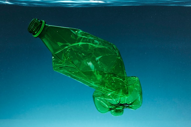 Photo crumpled plastic bottle polluting the ocean