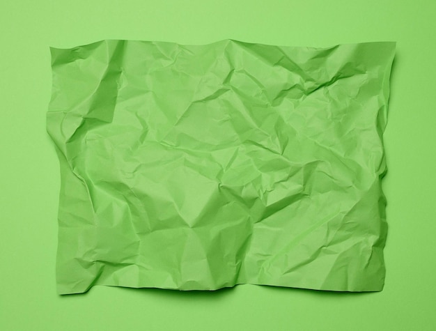 Crumpled rectangular sheet of green paper on a green background top view Place for inscription