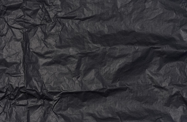 Crumpled sheet of black parchment paper abstract background
