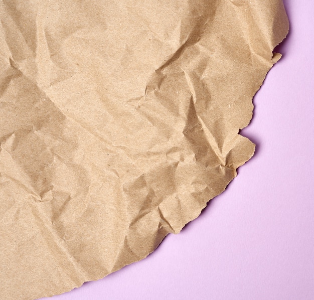 Photo crumpled sheet of brown wrapping paper on a purple background