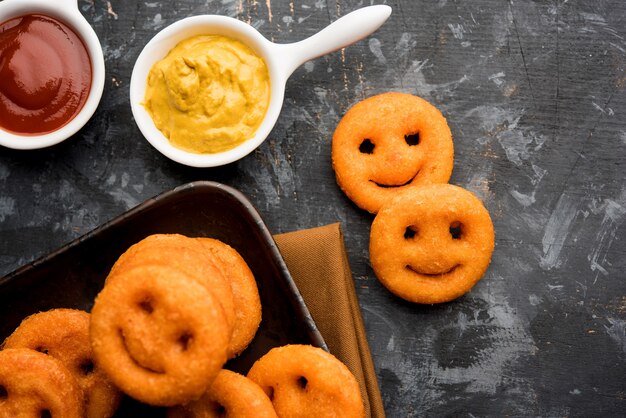 Crunchy potato smiling face chips or fried smile faced snacks served with ketchup