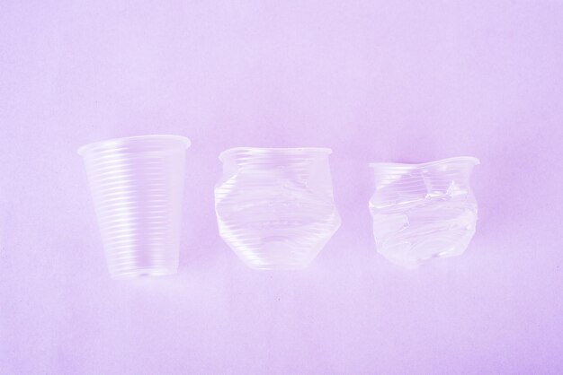 Crush transparent plastic drinks cups on the very peri background. zero waste concept. no plastic. top view. flat lay.