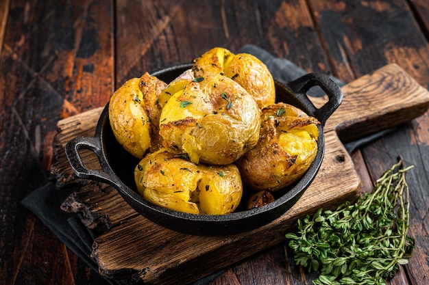 Crushed Broken potatoes baked in oil with herbs Wooden background Top view