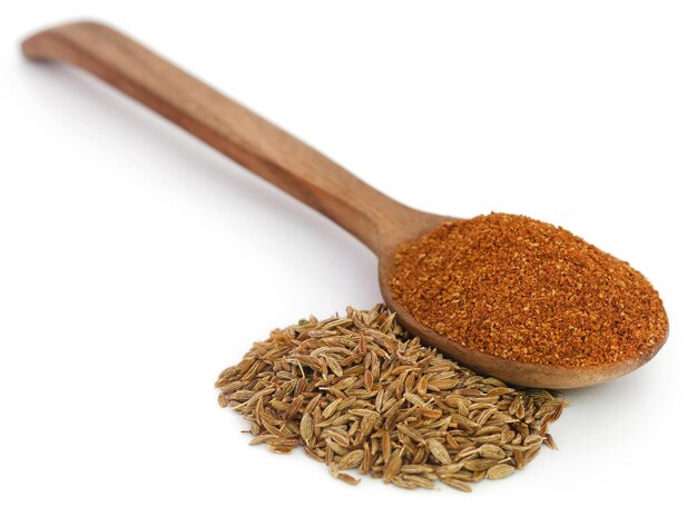 Crushed cumin with whole ones over white background