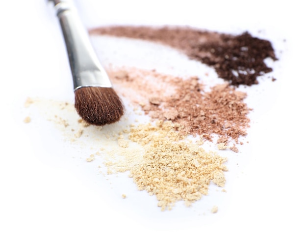 Crushed eyeshadow and professional makeup brush isolated on white