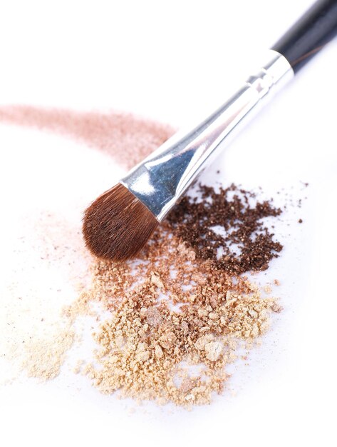 Crushed eyeshadow and professional makeup brush isolated on white