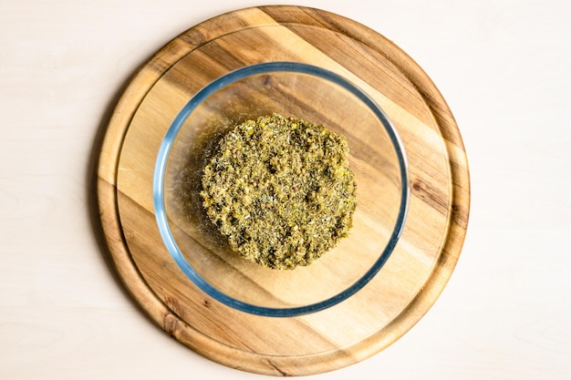 Photo crushed herbs and plants in glass bowl on board