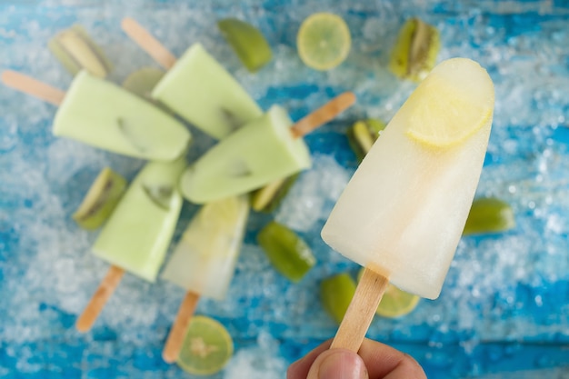 Crushed ice cubes and lemon, kiwi, homemade ice cream on vintage blue wooden table.